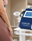 Adonis 30K body contouring machine with touchscreen display and multiple treatment handpieces beside a model in a spa setting.